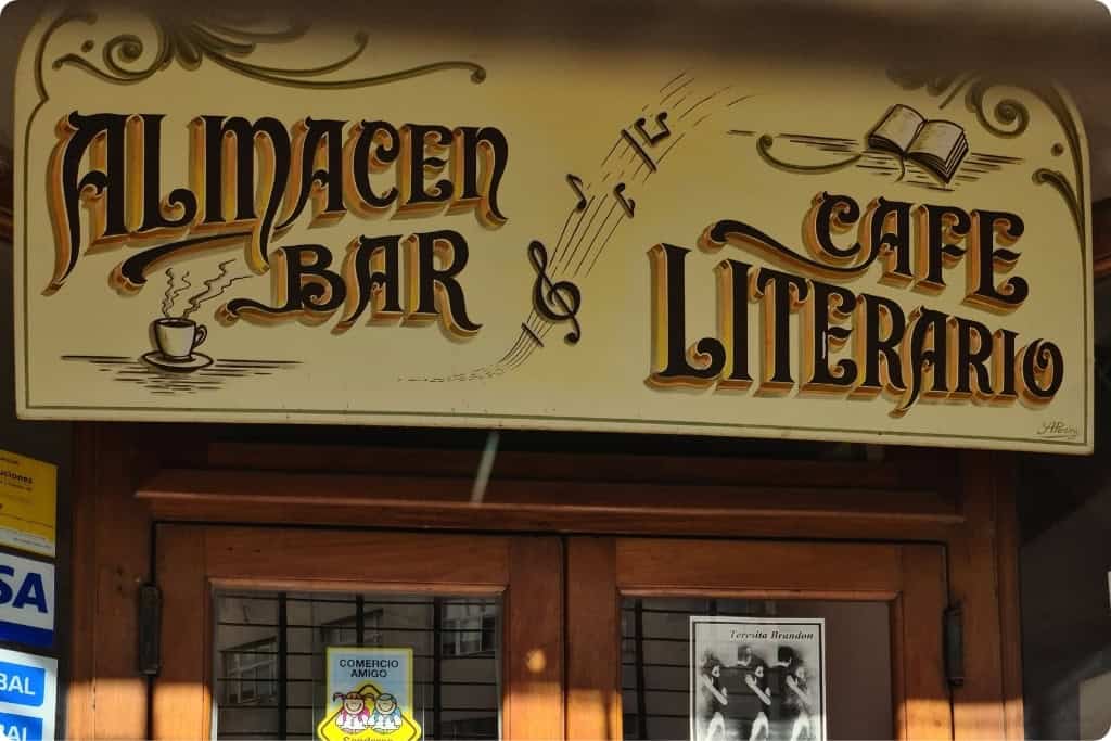 Vintage storefront sign for 'Almacen Bar & Cafe Literario' in Argentina, featuring traditional Fileteado Porteño design with elegant lettering, musical notes, and literary motifs, embodying the charm of Buenos Aires' cultural cafes.