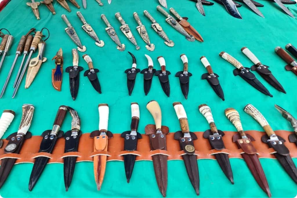 Display of traditional gaucho knives at an Argentinian market, featuring intricately crafted blades with wooden and horn handles, decorative sheaths, and cultural designs, ideal as unique Argentine souvenirs.