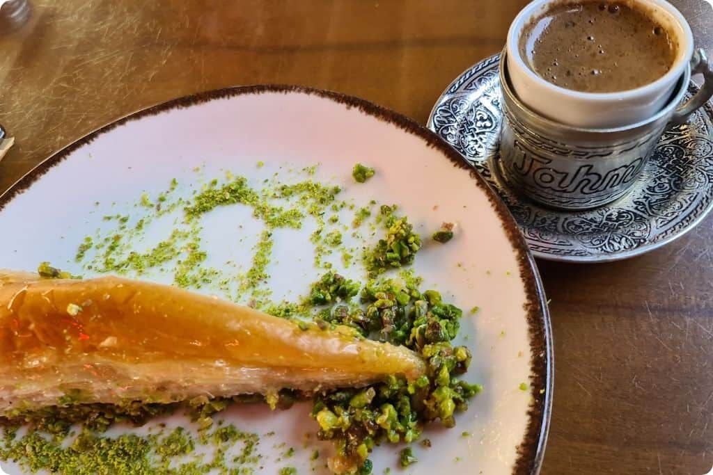 Delicious Antep-style baklava topped with crushed pistachios, paired with a cup of aromatic Menengic coffee served in a traditional Turkish cup, showcasing authentic flavors of Turkey.