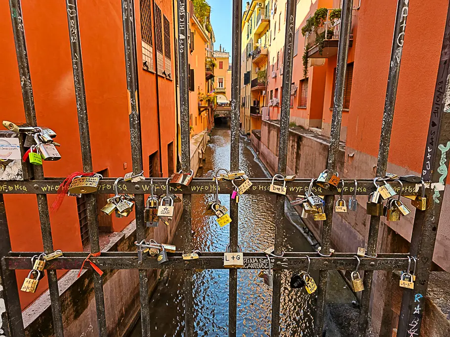 Close-up of padlocks on the railing overlooking Bologna’s hidden canal at Via Piella, a romantic photo location often called the “Little Venice” of Bologna.