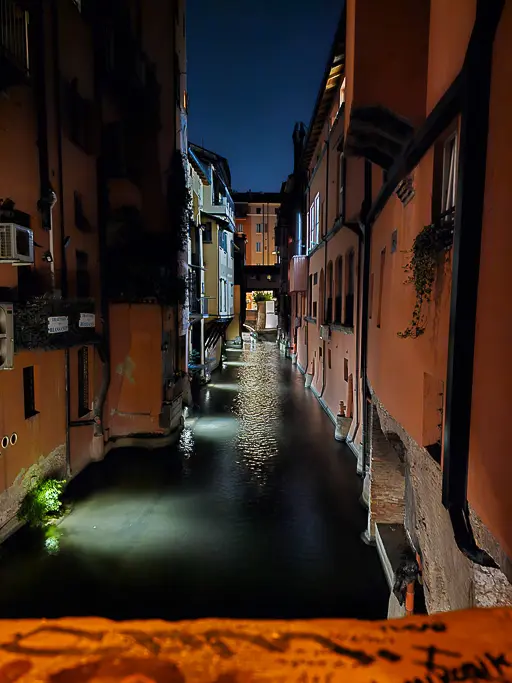 Nighttime view of Bologna’s secret canal from the Via Piella window, with moody reflections and warm lighting—perfect for low-light photography in Bologna.