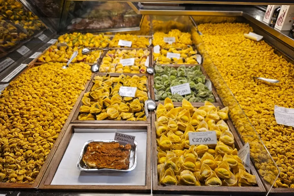 Variety of handmade tortellini, balanzoni, and tagliatelle pasta displayed at a fresh pasta shop in Bologna’s Quadrilatero Market, perfect for food photography and Italian gastronomy lovers.