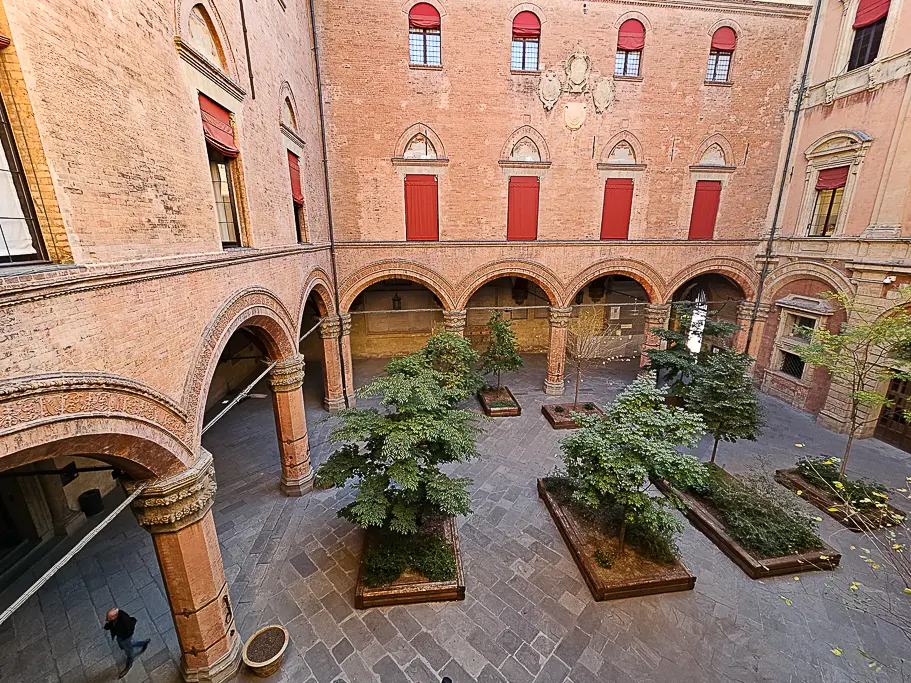 Inner courtyard of Palazzo d’Accursio in Bologna, featuring Renaissance arches and a tranquil garden—an underrated Bologna photo spot often missed by tourists.
