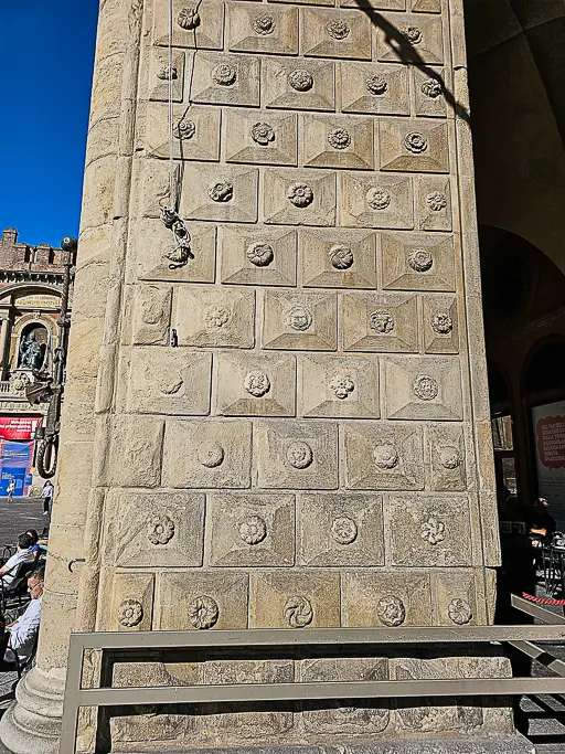 Geometric floral tile pattern carved into the wall at Palazzo del Podestà in Bologna, highlighting intricate medieval stonework and perfect for close-up architectural shots.