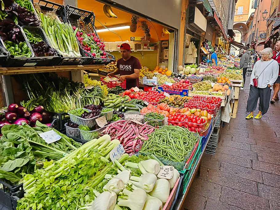 Colorful street market in Bologna’s Quadrilatero district filled with vibrant displays of local fruits and vegetables—perfect for food lovers and travel photographers seeking authentic Italian markets.