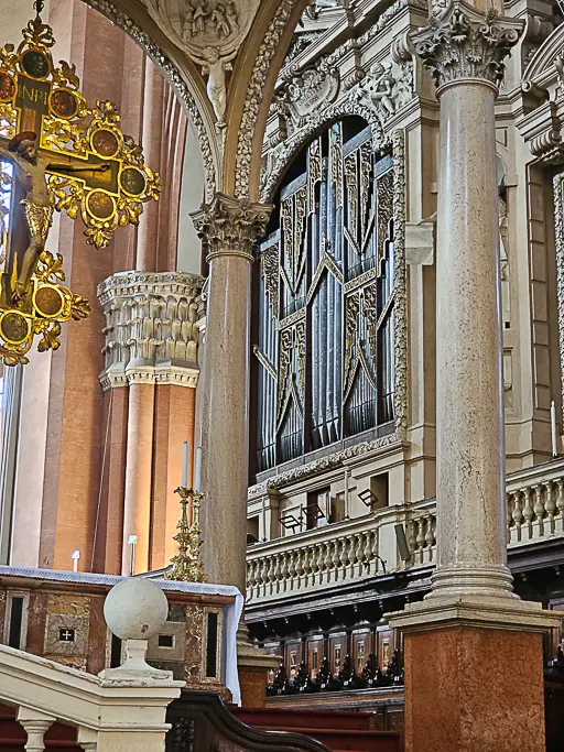 Close-up view of the historical pipe organ inside the Basilica di San Petronio in Bologna, Italy. This impressive instrument is considered the oldest functioning organ in the world, dating back to the 15th century, housed in an elaborate Baroque frame above the choir stalls.