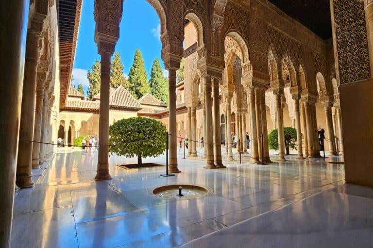 Stunning view of the intricate Islamic architecture and marble columns at the Court of the Lions in the Alhambra Palace, one of the top attractions in Granada, Spain.