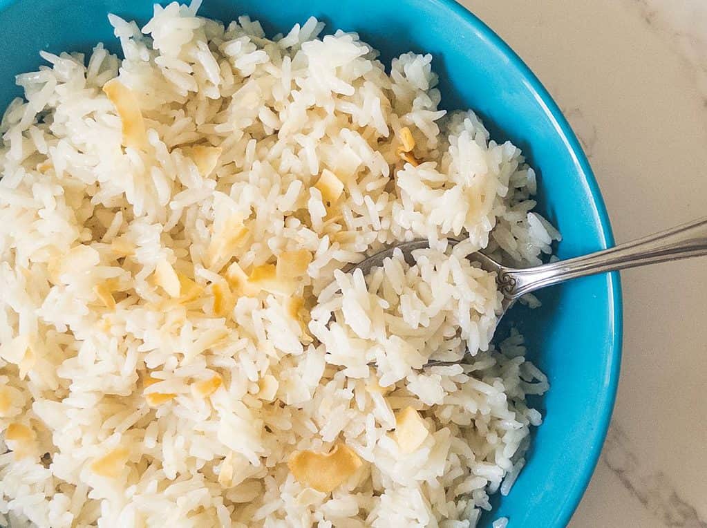 Coconut rice with toasted coconut in blue bowl with spoon