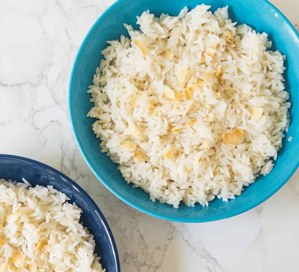 Two blue bowls containing rice with toasted coconut
