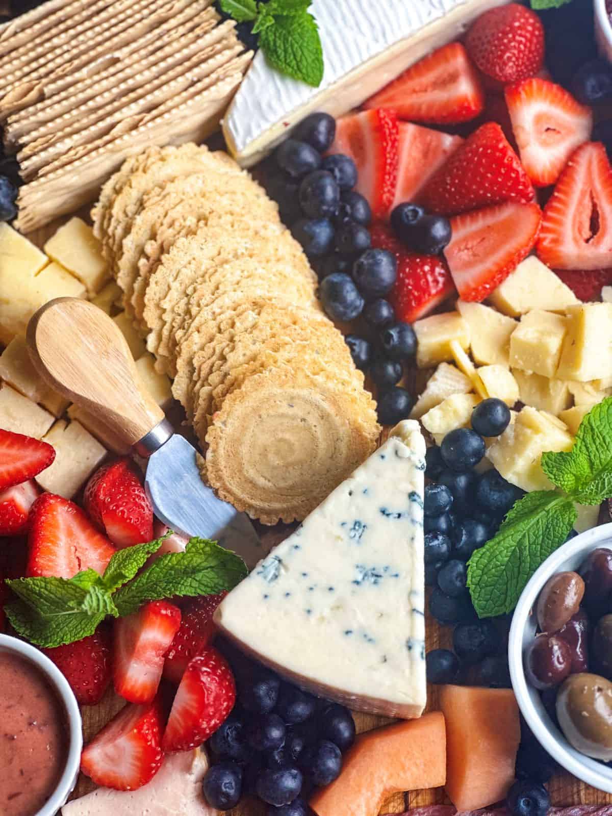 Charcuterie board with blue cheese, fruit, and olives.