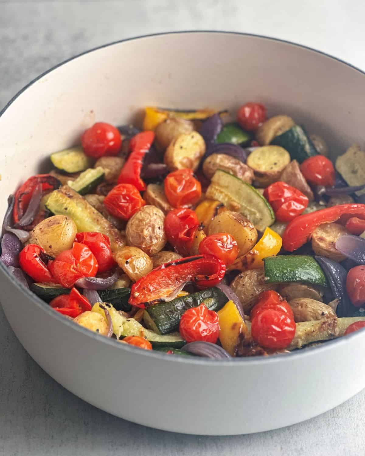 Italian roasted vegetables in a white Le Creuset pan.