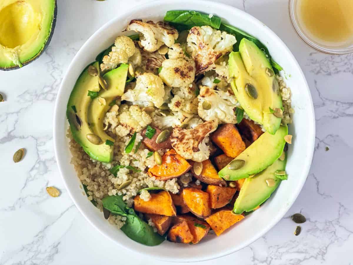 Bowl with quinoa, sweet potato, cauliflower, avocado and pepita seeds.
