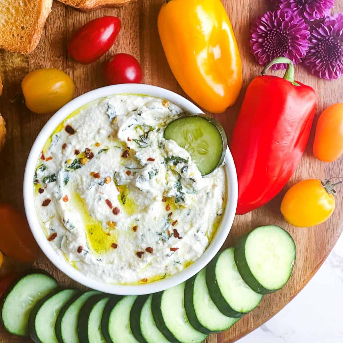 Creamy whipped ricotta dip in a bowl with veggies around it.