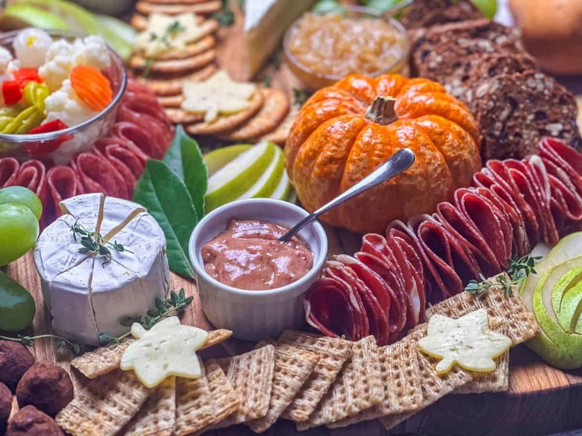 Cranberry honey mustard in a ramekin on a fall charcuterie board with crackers, meats, and cheeses.