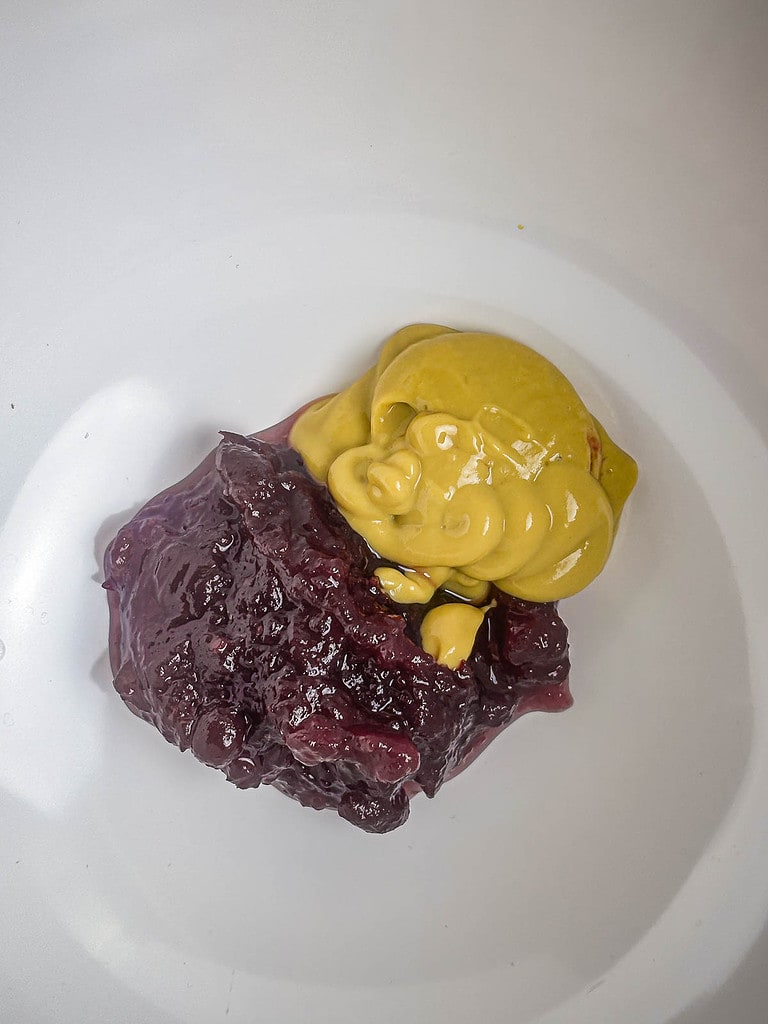 Cranberry sauce and honey mustard in a white bowl before mixing.
