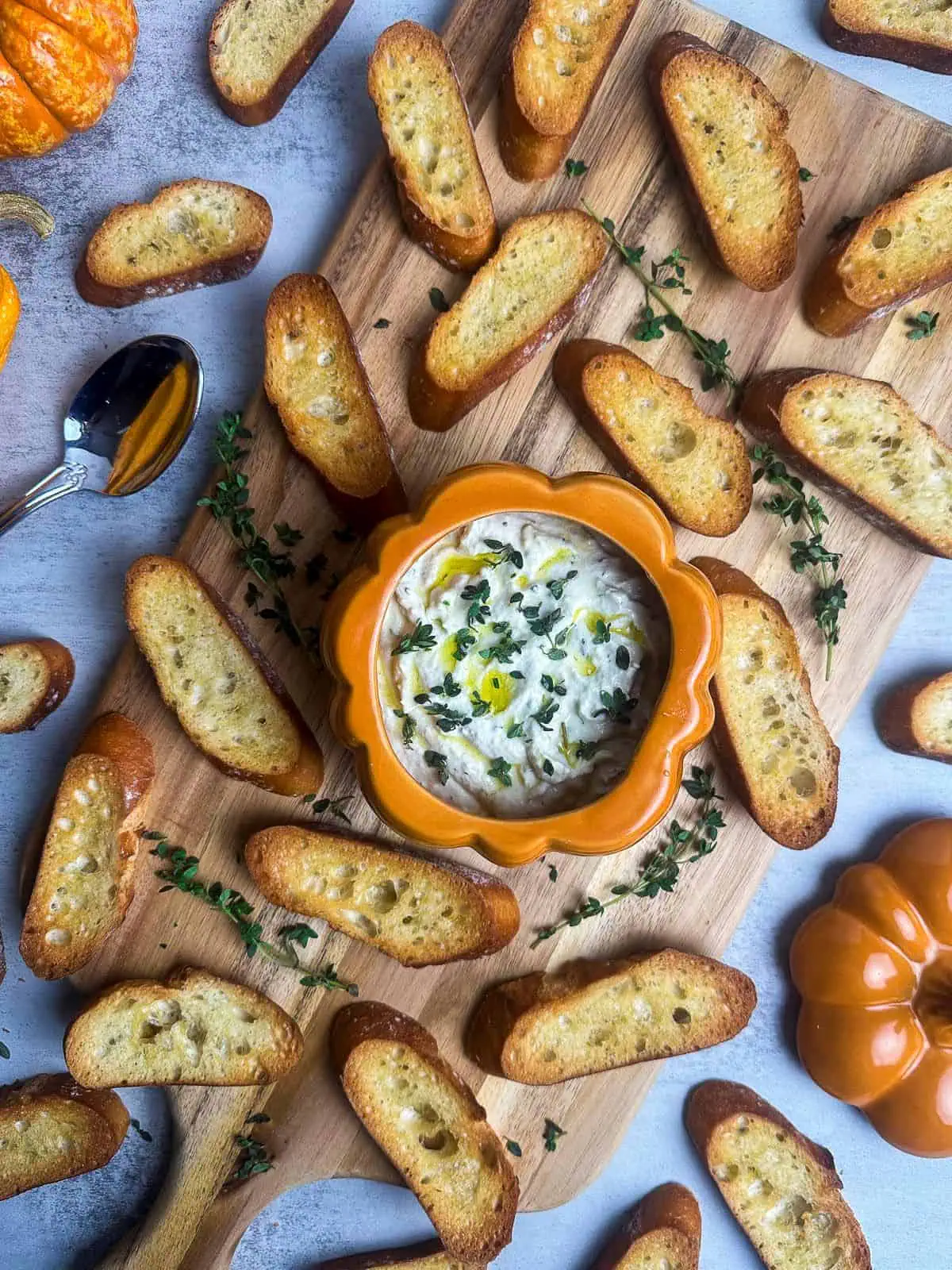 Truffle burrata dip on a board with crostini and fresh thyme.