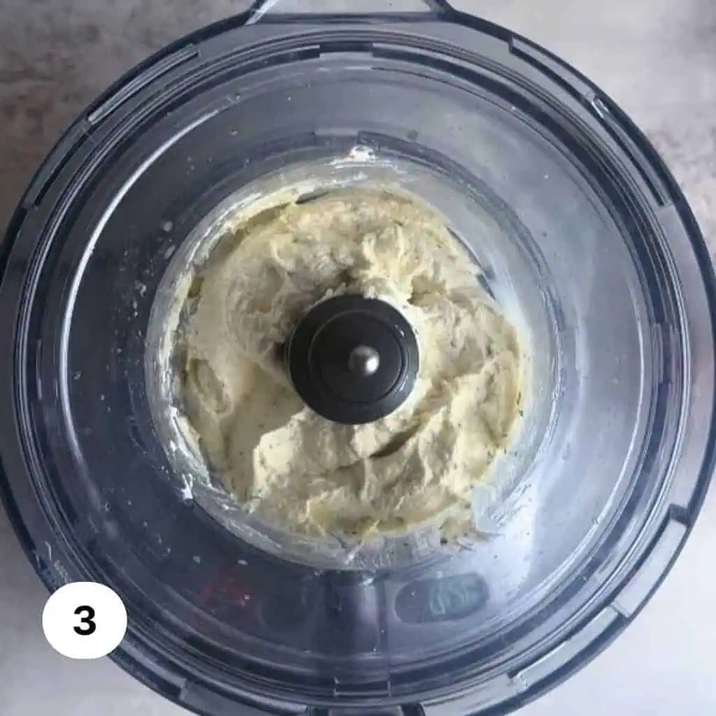 Whipped burrata truffle dip in the bowl of a food processor.
