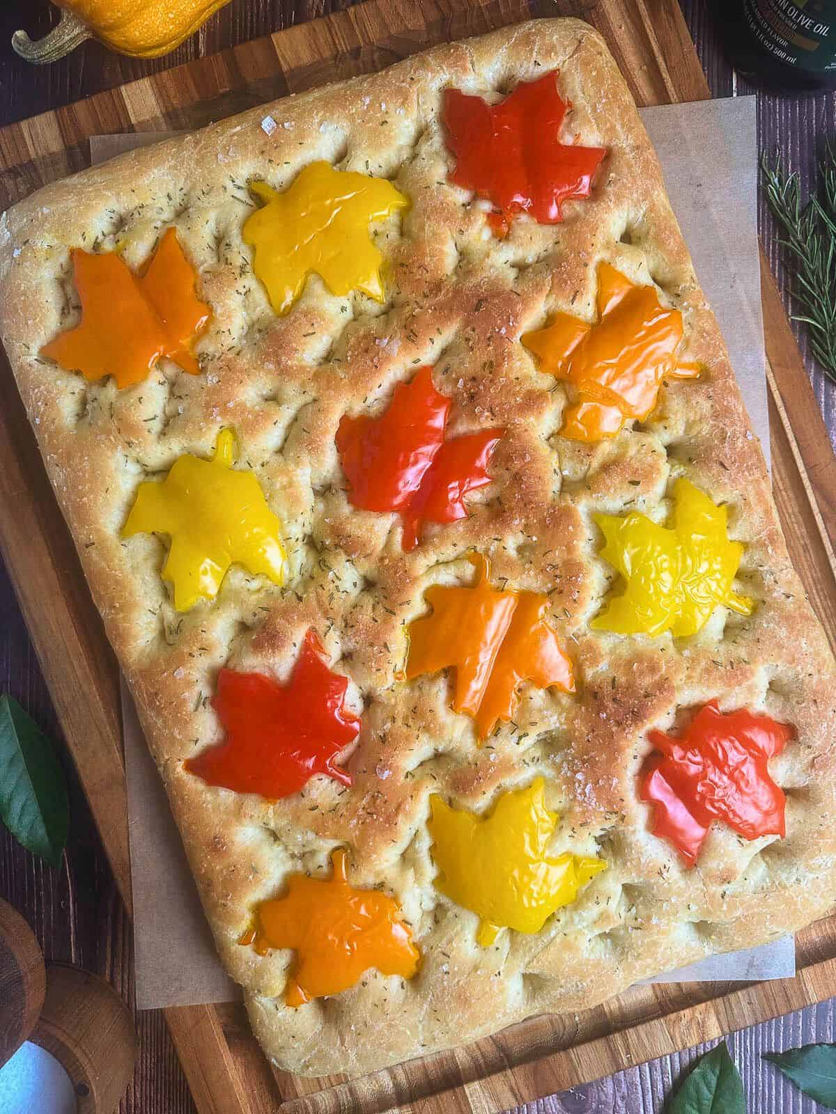 Fall focaccia bread topped with maple leaf shaped red, orange, and yellow bell peppers.