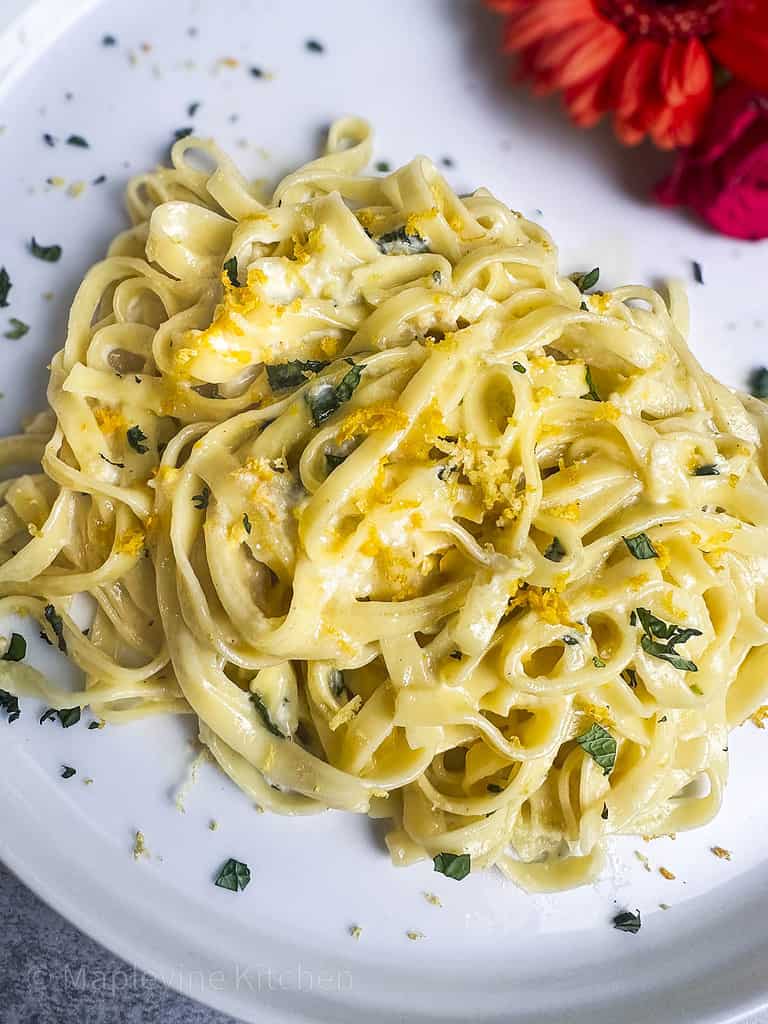 Close up shot of pasta magnifico on a round white plate with citrus zest and fresh mint garnish.