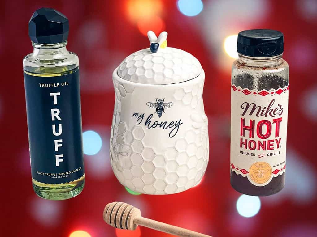 A honey jar and bottles of hot honey and truffle oil on a red background.