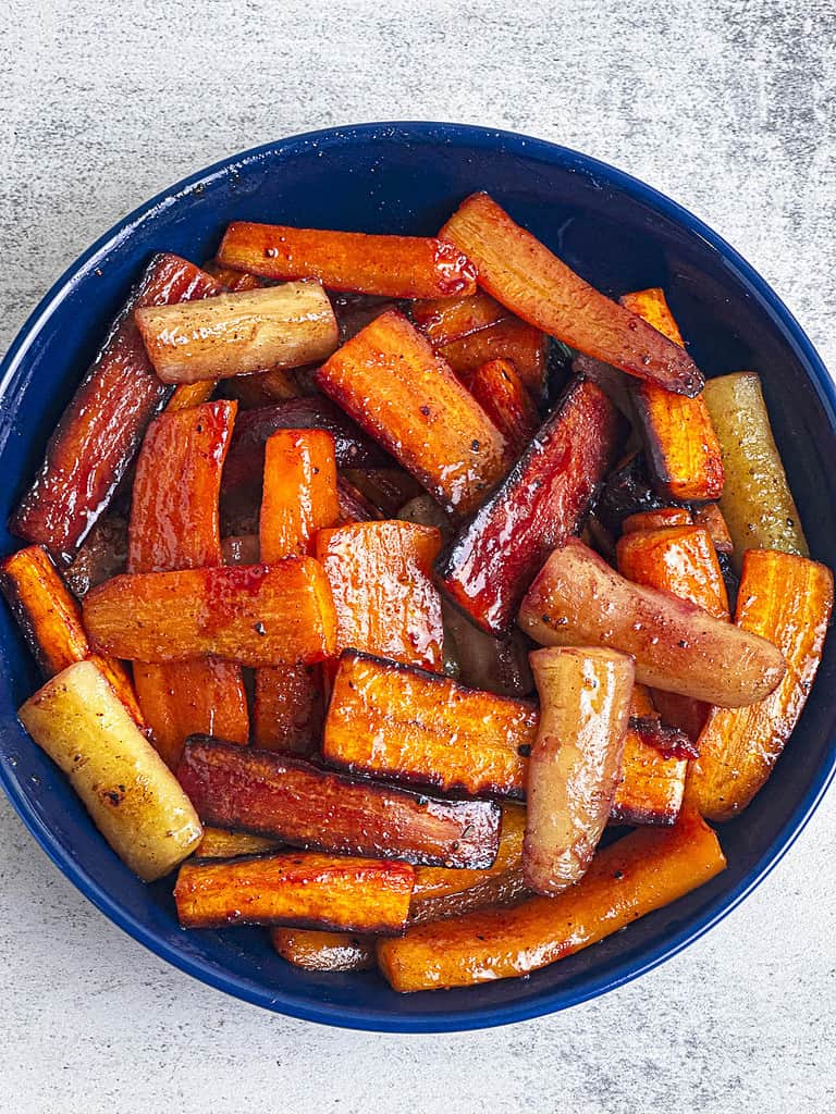 Hot honey carrots with warming spices in a dark blue bowl.