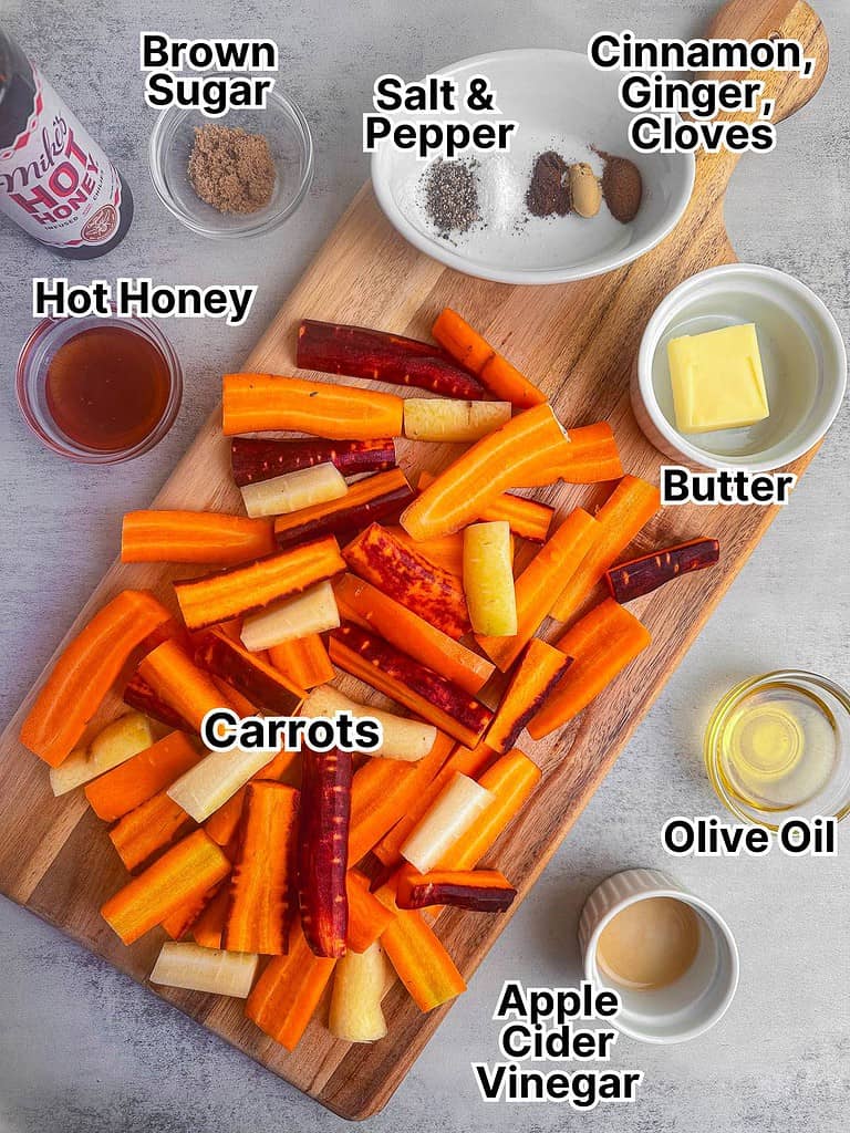Ingredients for hot honey carrots displayed on a cutting board on a gray counter top.