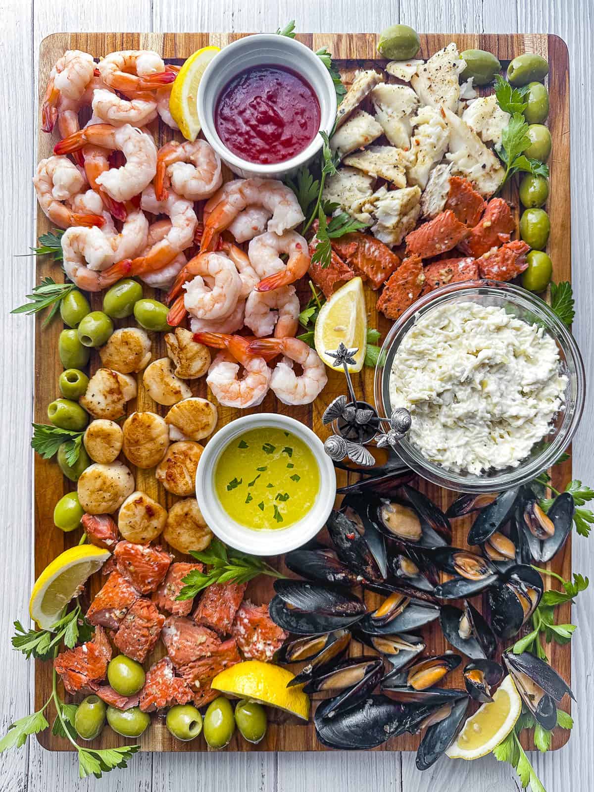 Large rectangular charcuterie board with seafood including mussels, salmon, scallop, and prawns.