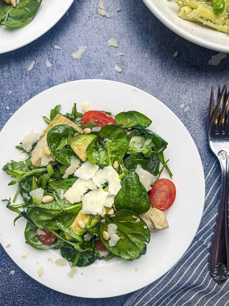 Spinach and arugula salad on a small white salad plate with forks on the side.
