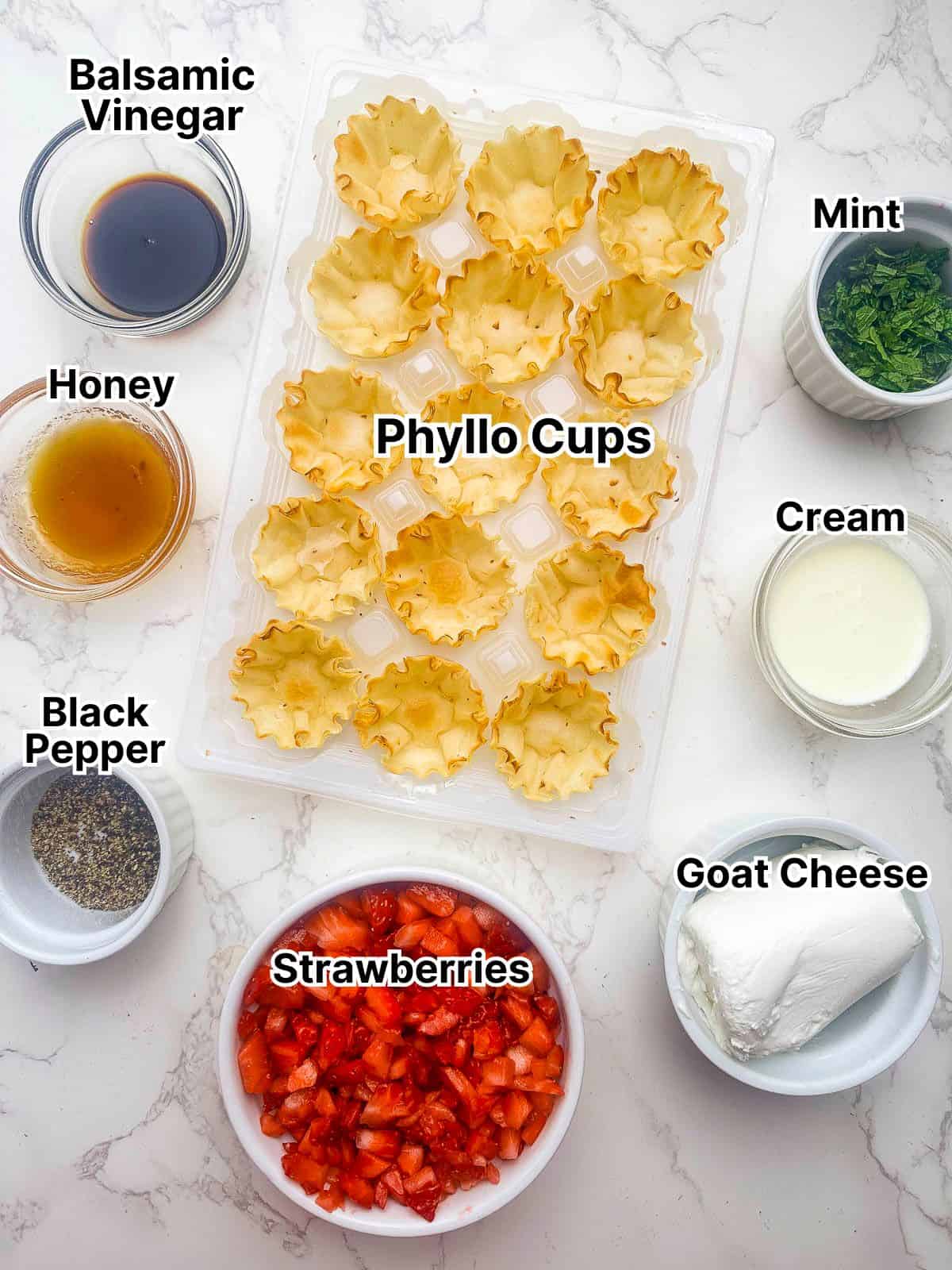 Phyllo cups, goat cheese, strawberries, and other recipe ingredients in small bowls.