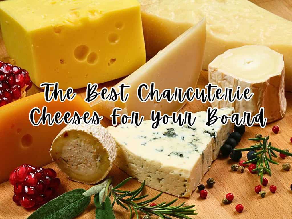 Several different cheeses on a wooden surface with pomegranate seeds and rosemary twigs surrounding.