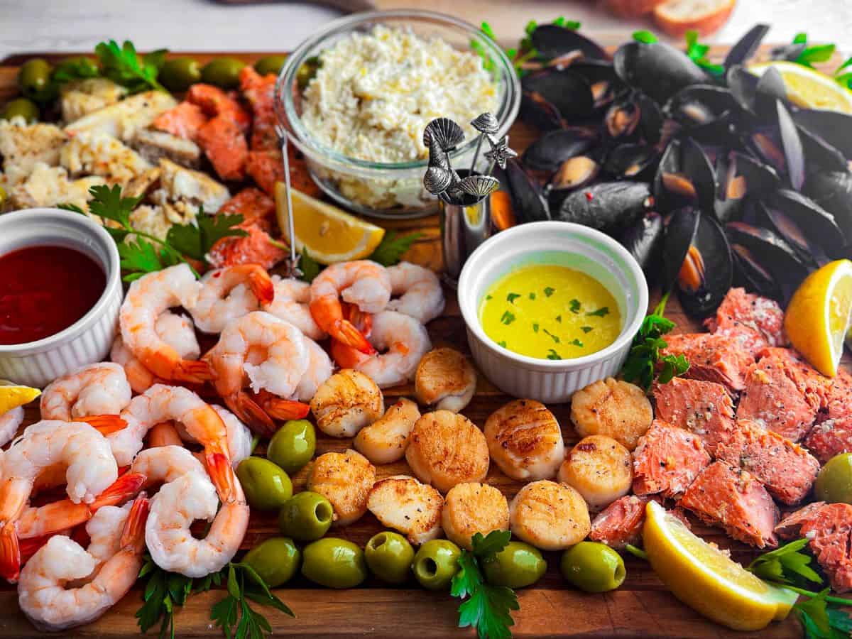 Various seafood on a charcuterie board with ramekins and skewers.