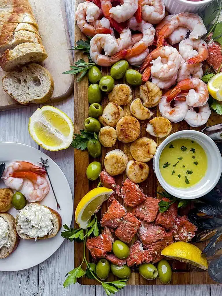 Seafood on a wooden cutting board with slices of bread on the side.