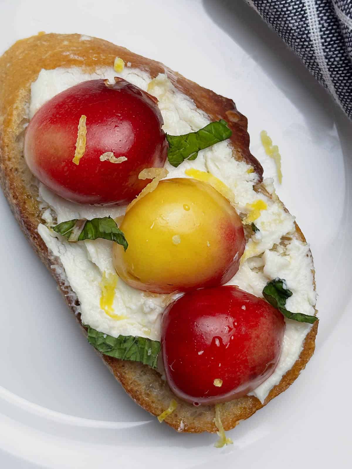 A goat cheese and cherry crostini on a white plate.