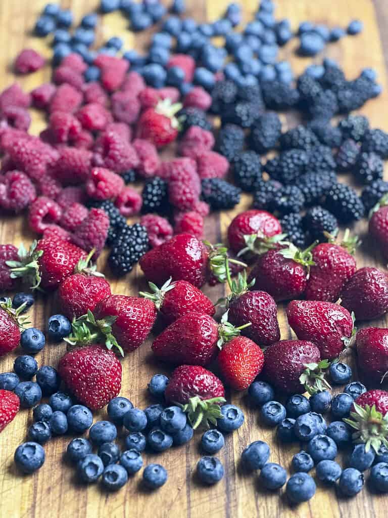 Summer berries on a wooden cutting board.