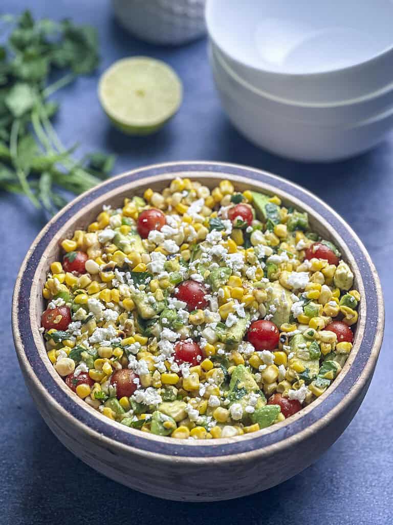 Charred corn salad with tomato, avocado, and feta in a bowl.
