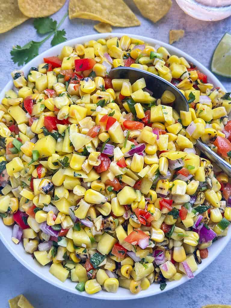 Mango corn salsa in a bowl with a spoon.