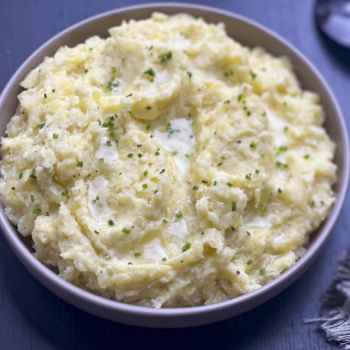 Mashed potatoes with truffle oil and chives in a beige bowl