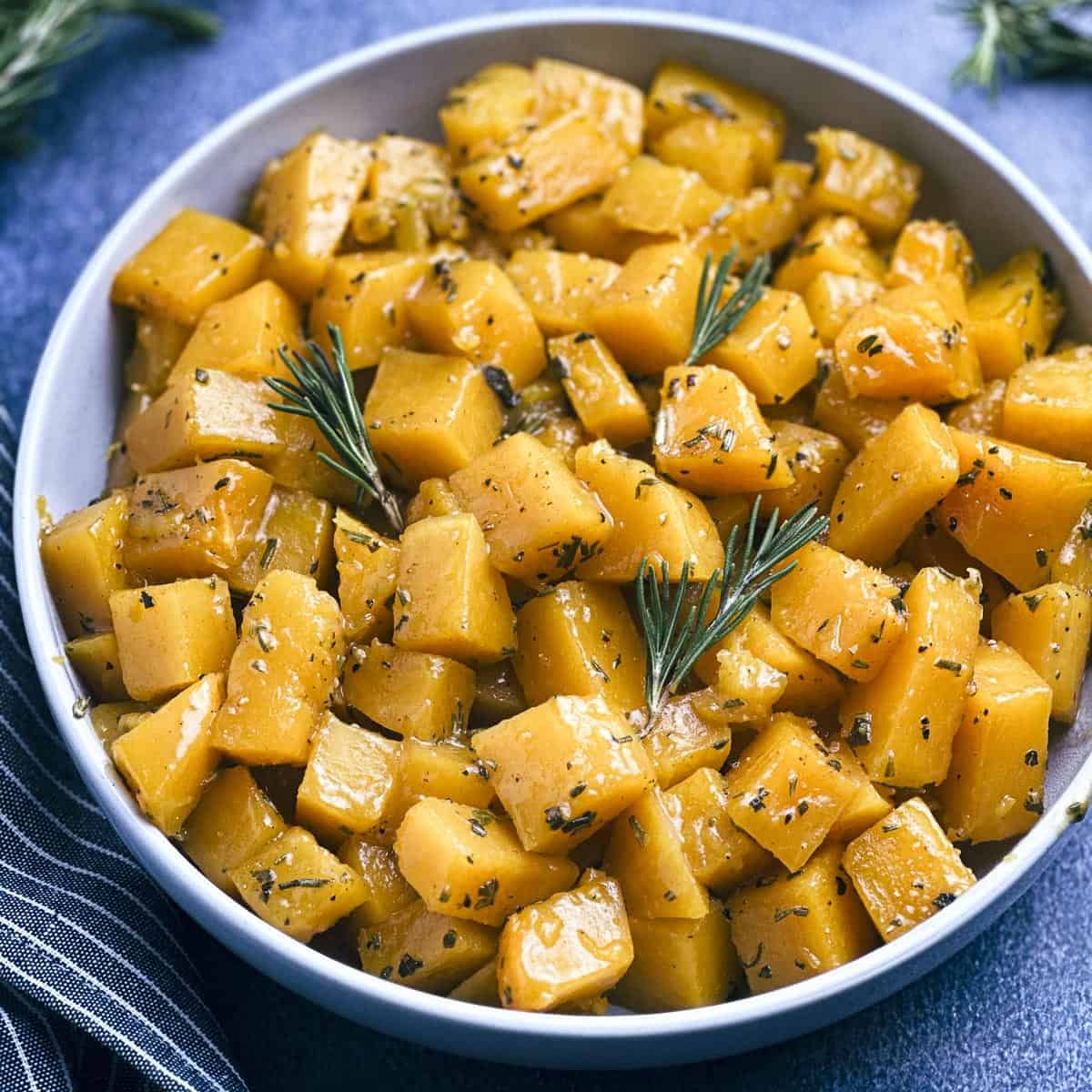 Apple cider glazed butternut squash with fresh rosemary in a grey bowl
