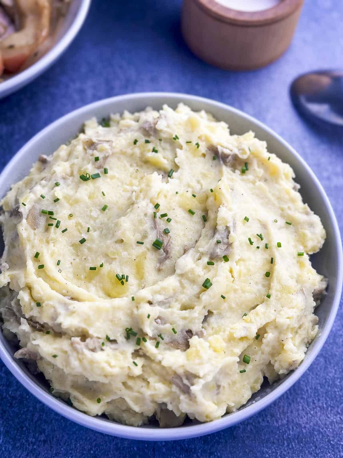 Yukon Gold mashed potatoes in a bowl with chives on top for garnish.