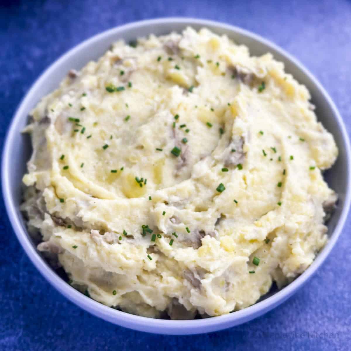 Swirled mashed potatoes with chives in a grey bowl