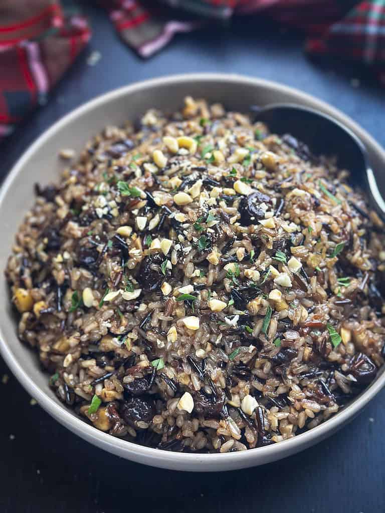 Wild rice, dried cherries, hazelnuts in a beige bowl.