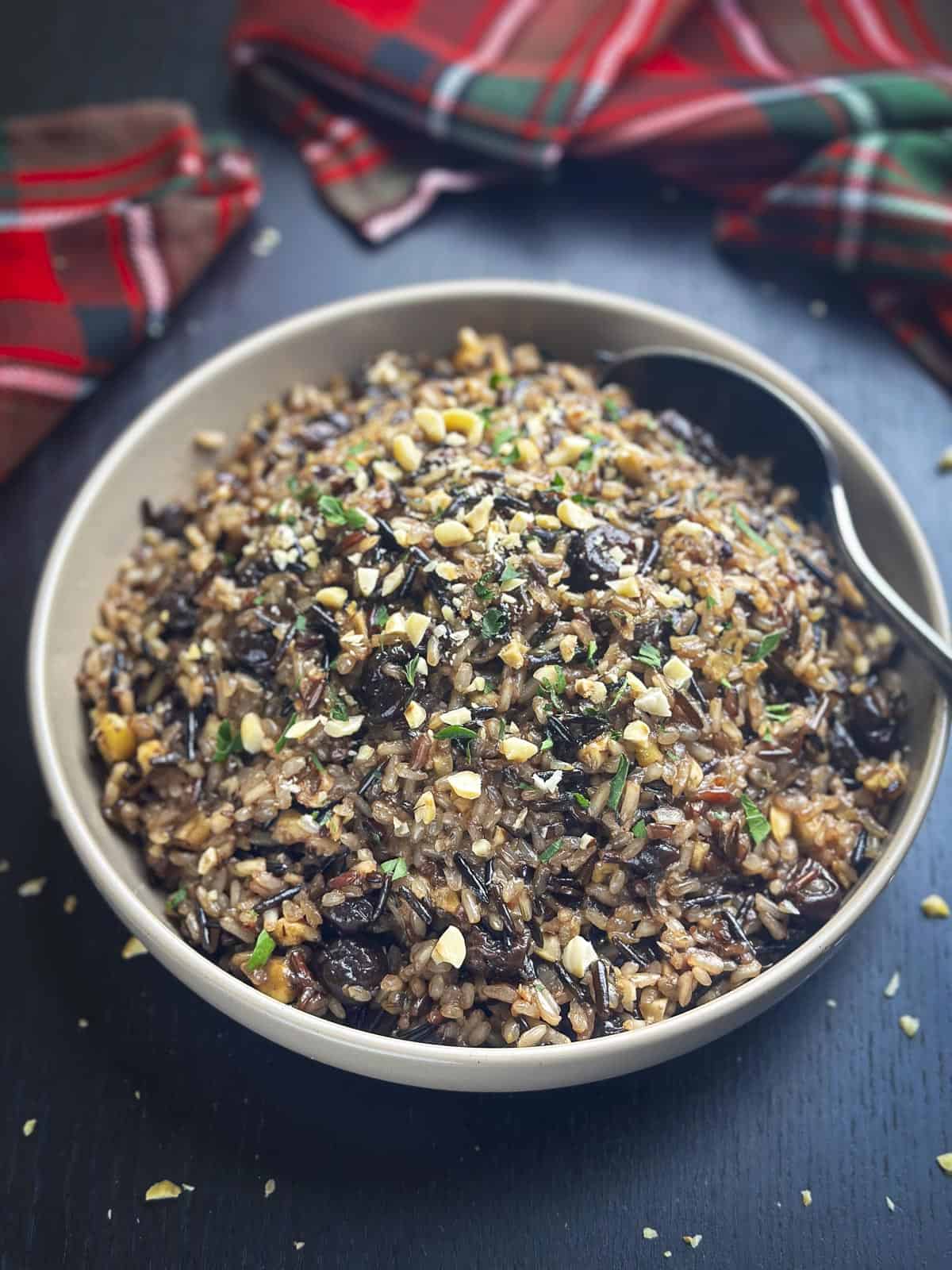 Wild rice with cherries, shallots, and hazelnuts in a beige bowl.