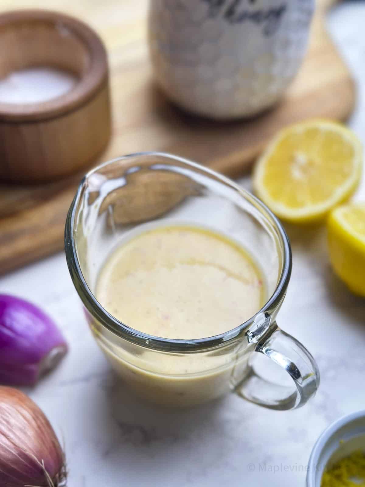 A glass carafe filled with a creamy lemon shallot dressing.