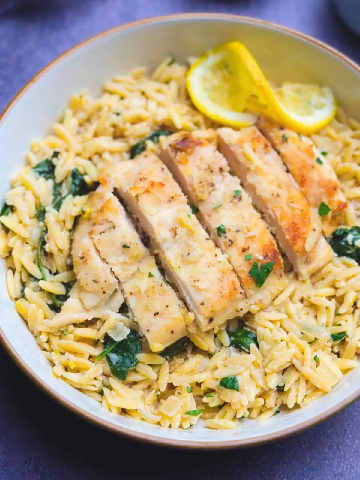 Creamy lemon chicken orzo with the chicken breast sliced on top of the orzo.