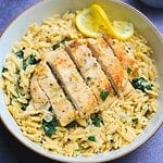 Creamy lemon chicken orzo with the chicken breast sliced on top of the orzo.