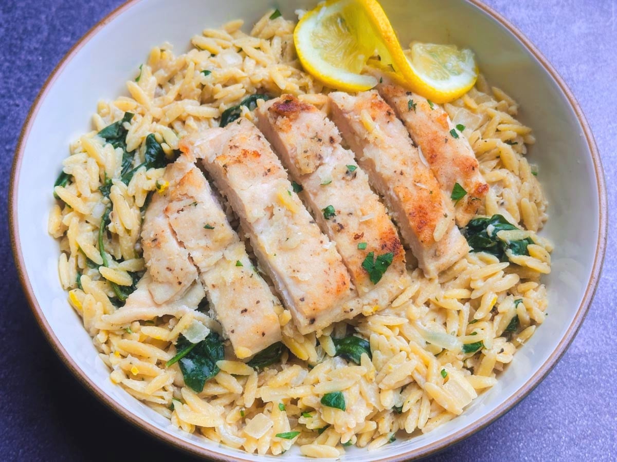 Crispy lemon chicken served over orzo pasta with lemon slices and parsley.