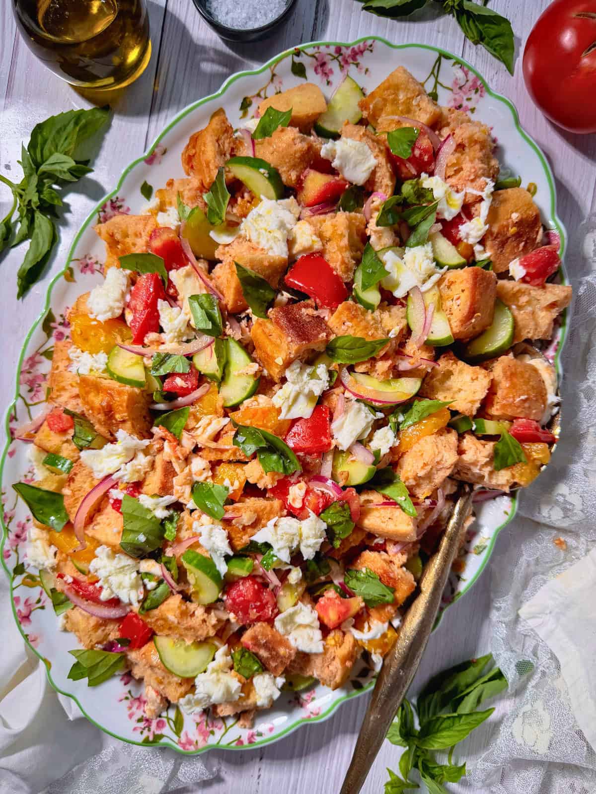 Panzanella salad with fresh mozzarella on a serving platter on a white table top.