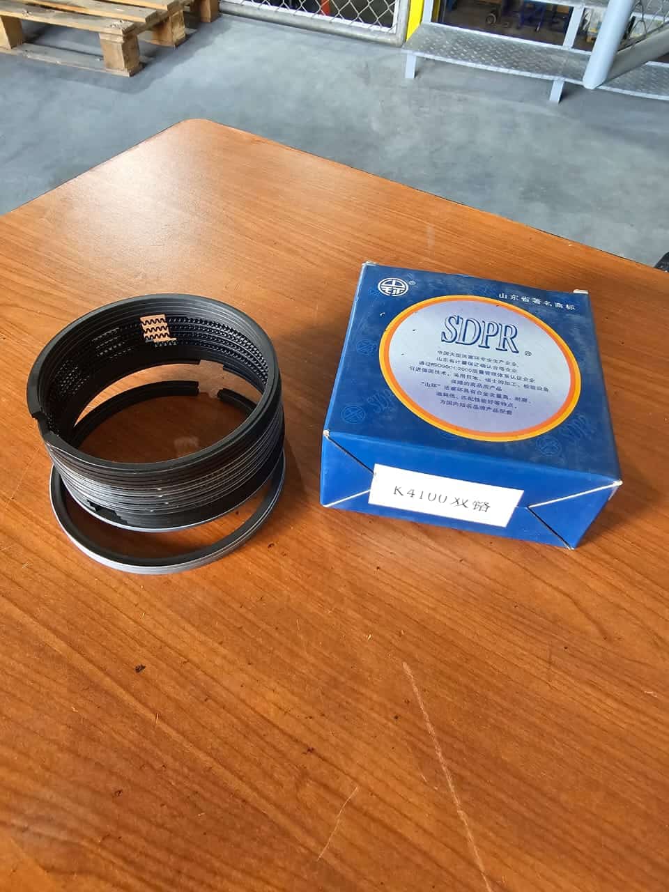 Anillo de retenedor de rodamientos SKF y caja de embalaje azul con logotipo SDPR en una superficie de madera. Ideal para mantenimiento y reparación de maquinaria industrial.