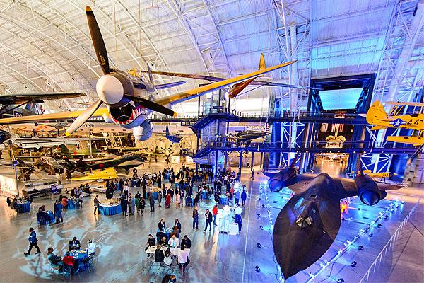 Indoor aviation museum with large aircraft displays and visitors exploring.