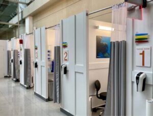 Medical testing booths with curtains and chairs in a clinical setting.